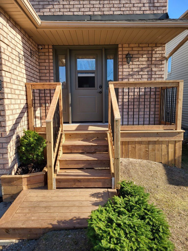 Wooden entrance stairs with custom railing against brick house